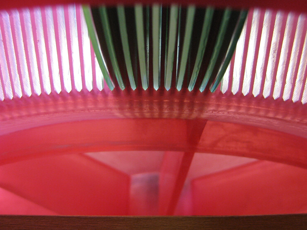 Edges of optical discs seated between the ribs of a red carousel prototype.