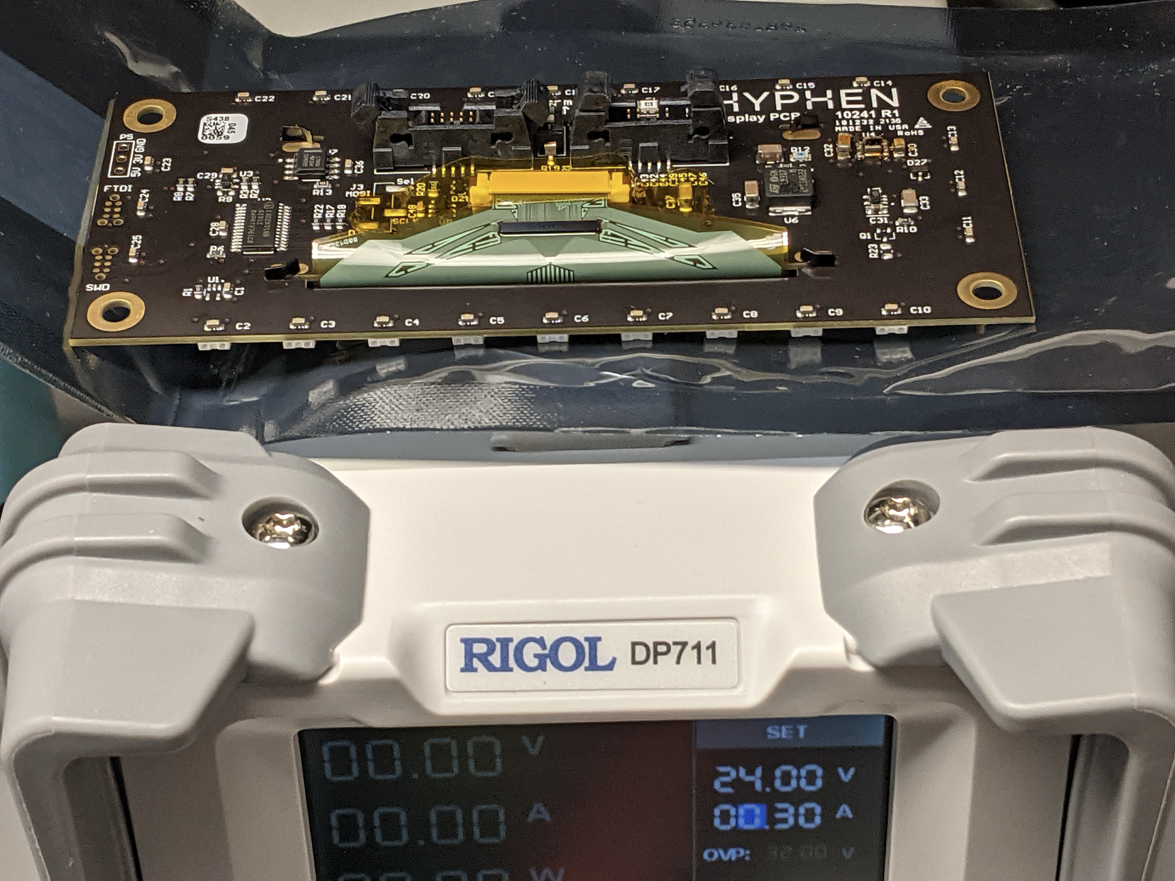 A rectangular display board photographed beside a bench power supply.