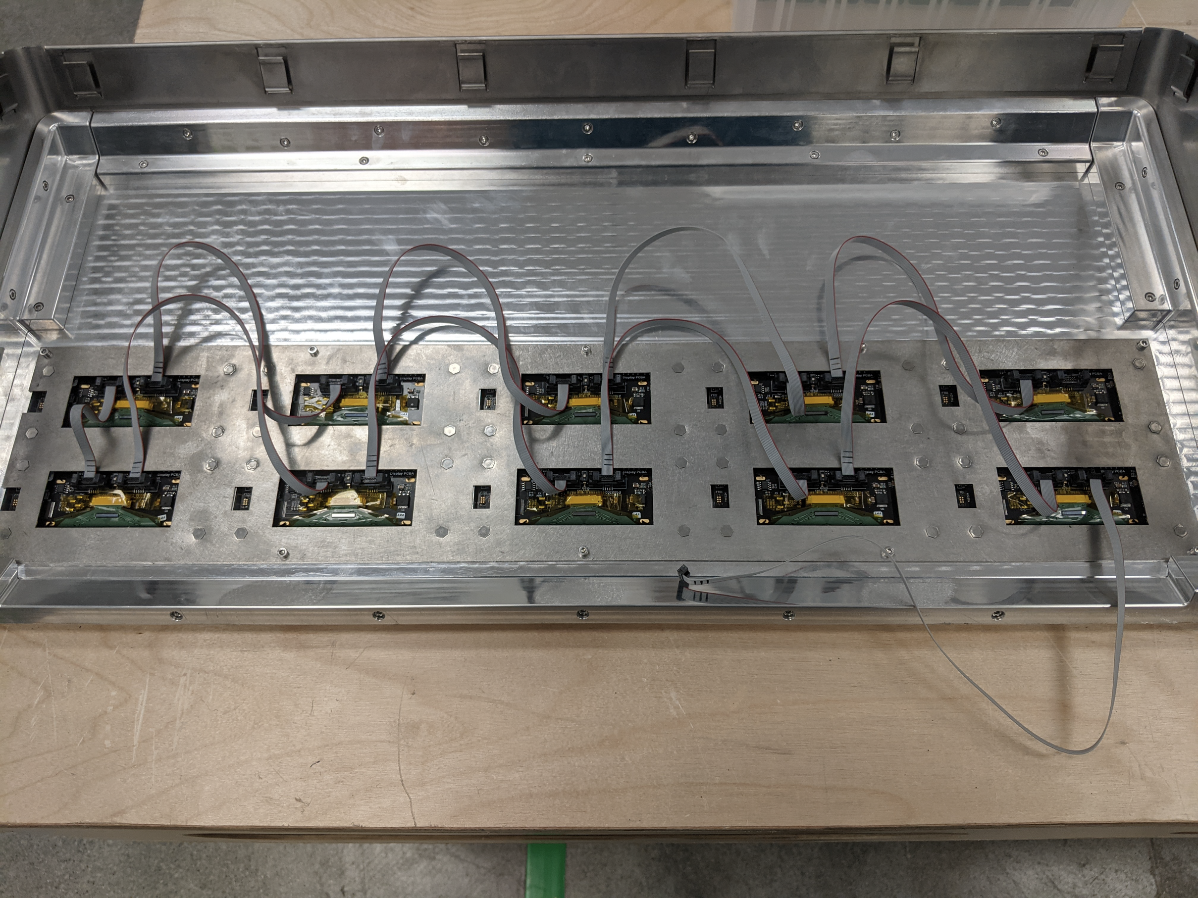 Rear of a display panel with two rows of small boards connected by gray ribbon cables.