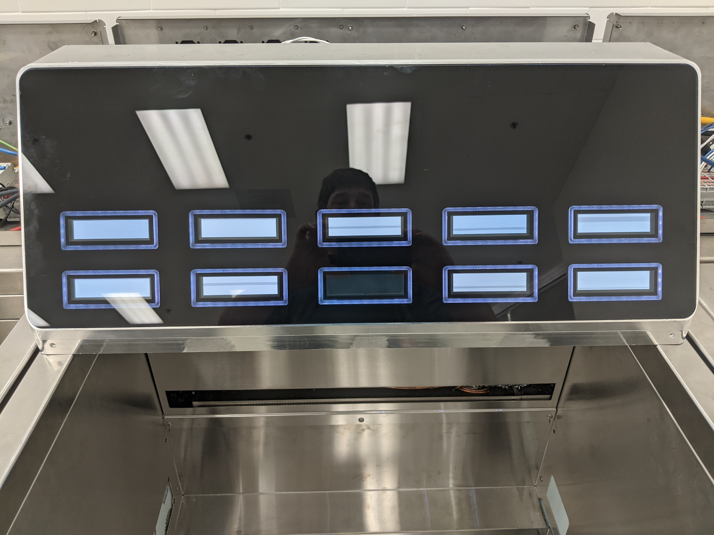 Ten rectangular display windows in two rows within a dark front face, with blue illuminated surrounds.