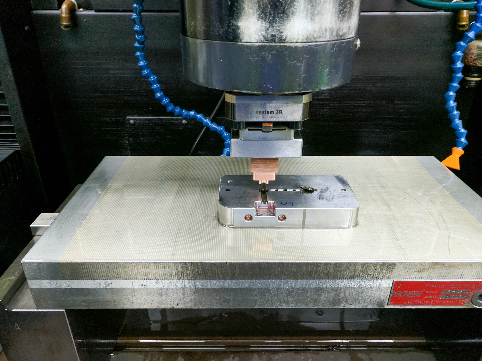 Copper-colored electrode positioned above a metal tool insert on a machine table.