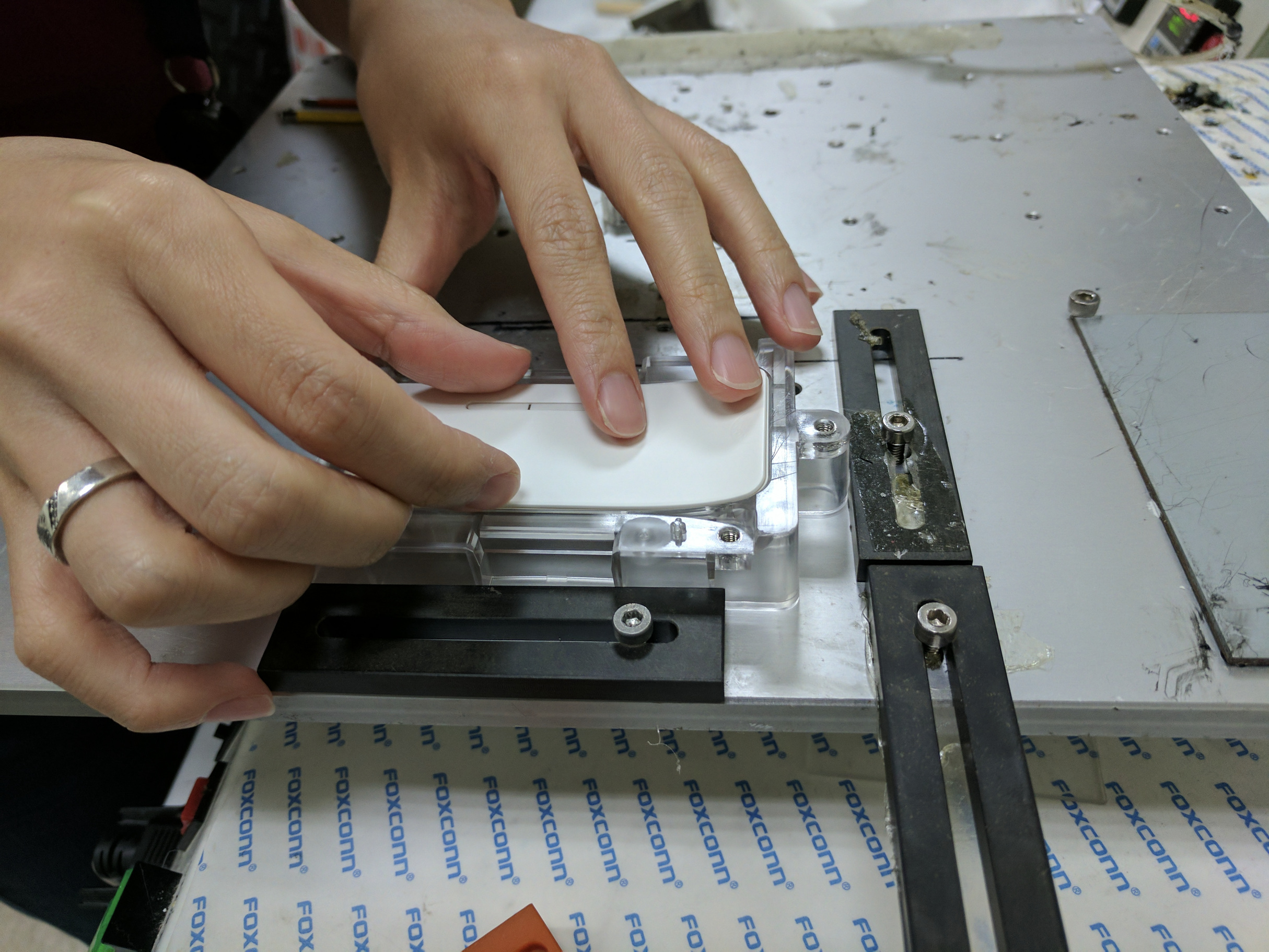 Hands placing a white plastic cap onto the front housing in the fixture.