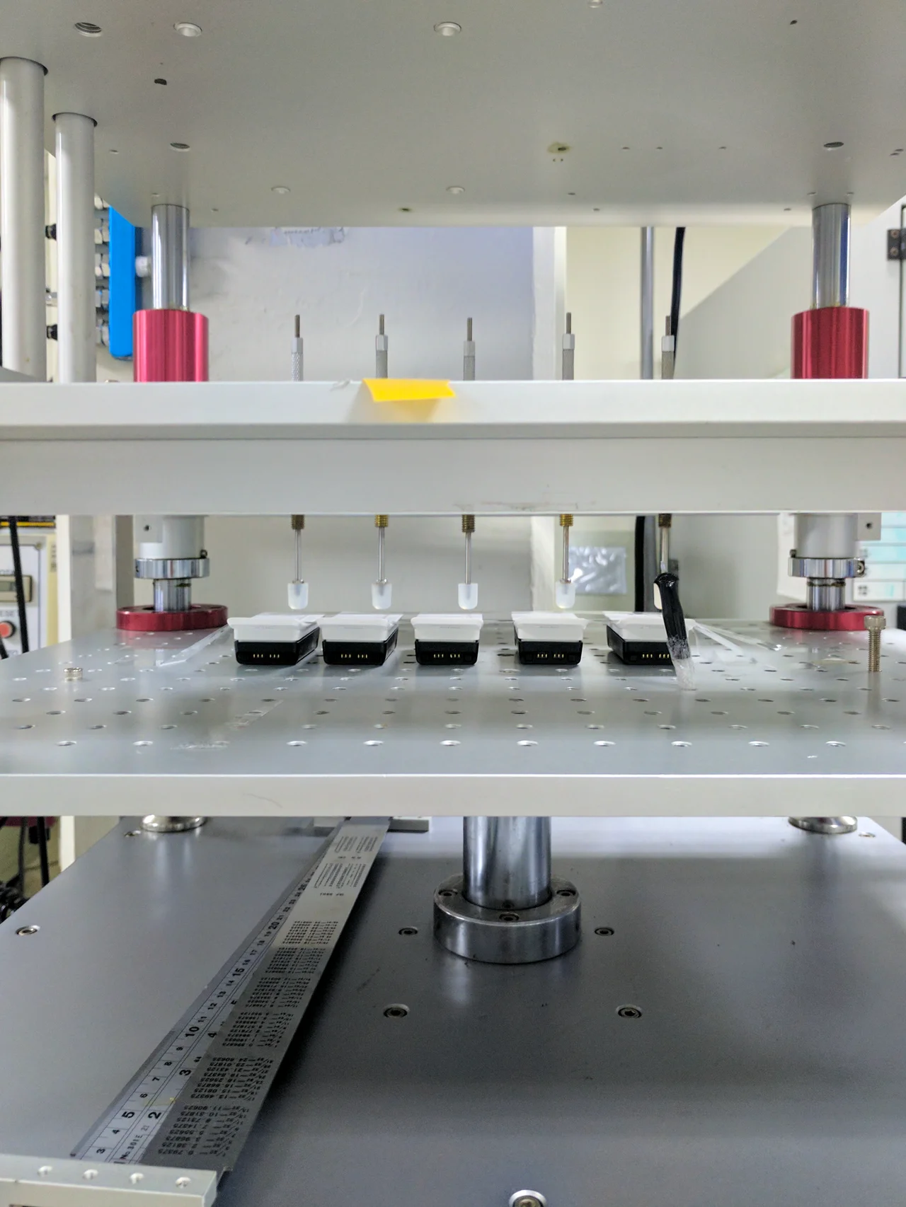 Several white switch assemblies beneath vertical actuators on a test rig.