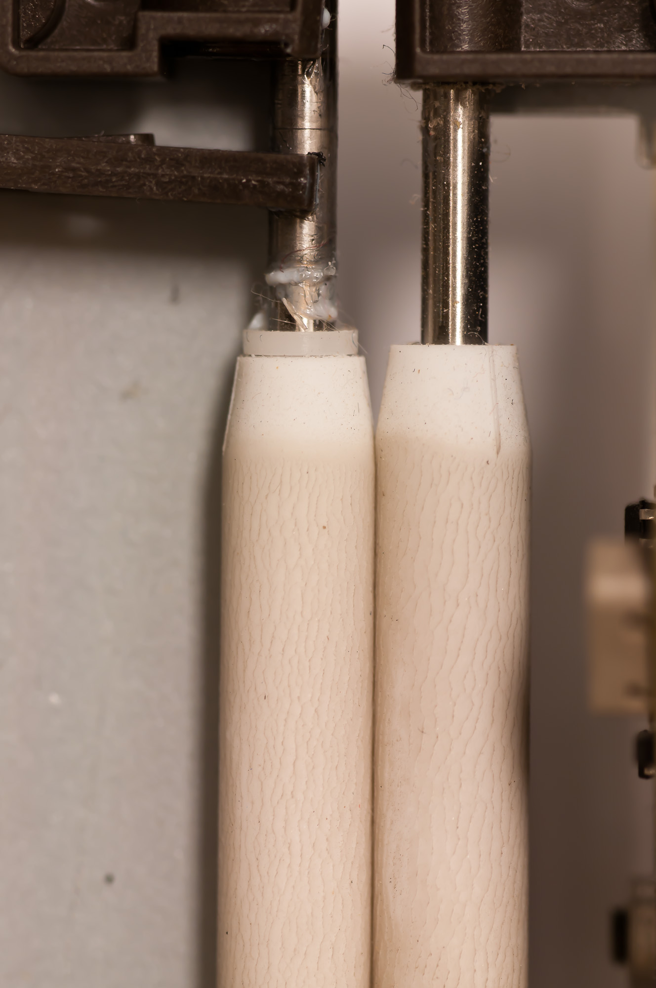 Close-up of white pinch rollers and steel shafts, with visible fibers and residue around the shaft supports.